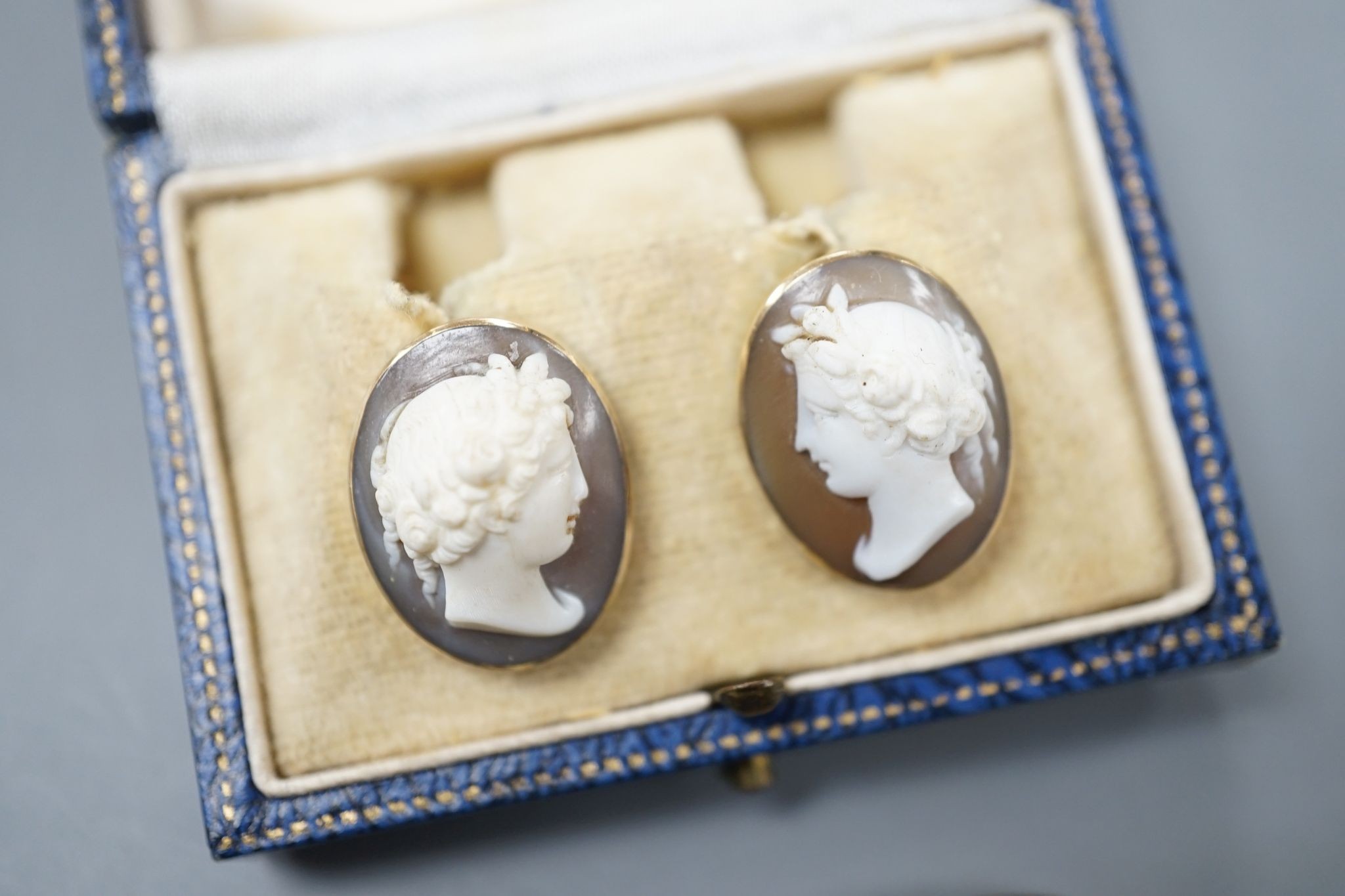 A yellow metal and hardstone set cameo ring, size J (a.f.), gross 6.9 grams, a pair of similar cameo shell ear clips and one other cameo shell mount.